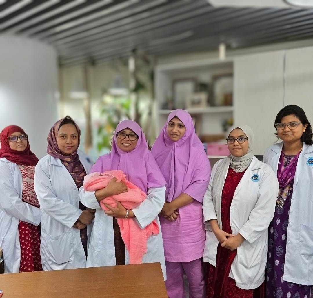 A clinical photograph of sterile surgical gloves holding hands gently in an operating theatre, representing medical compassion, surgeon warmth, clean medical environment in soft pink and teal tones.